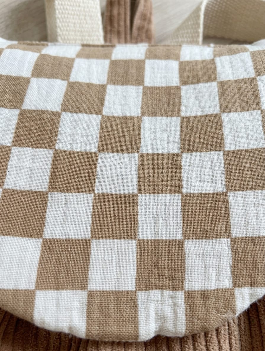 détail du tissu damier écru camel et café du sac à dos maternelle