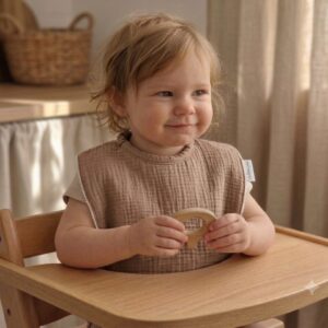 bavoir maternelle marron en gaze de coton porté par un enfant pendant le repas
