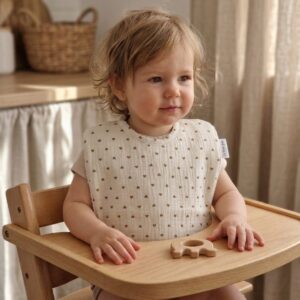 bavoir maternelle à cœurs marrons porté par un enfant pendant le repas
