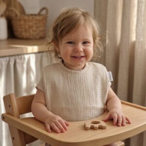 bavoir maternelle sable porté par un enfant en chaise haute