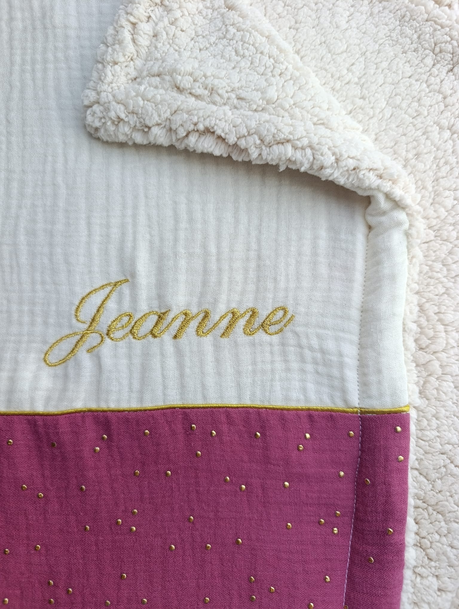 détail du prénom brodé sur une couverture personnalisée bébé en gaze de coton framboise dorée